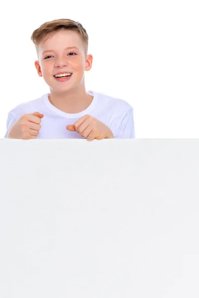 Um menino em idade escolar perto de um banner publicitário branco . — Fotografia de Stock