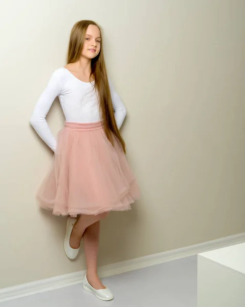Ein kleines Mädchen mit langen seidigen Haaren in der Nähe der Wand. — Stockfoto