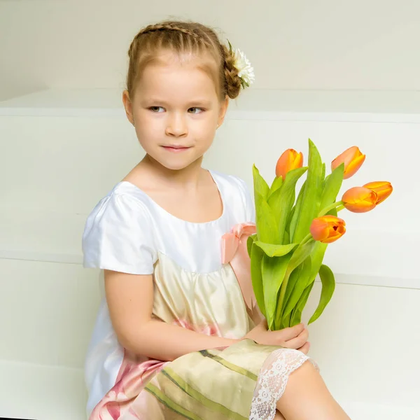 Klein meisje met een boeket tulpen. — Stockfoto