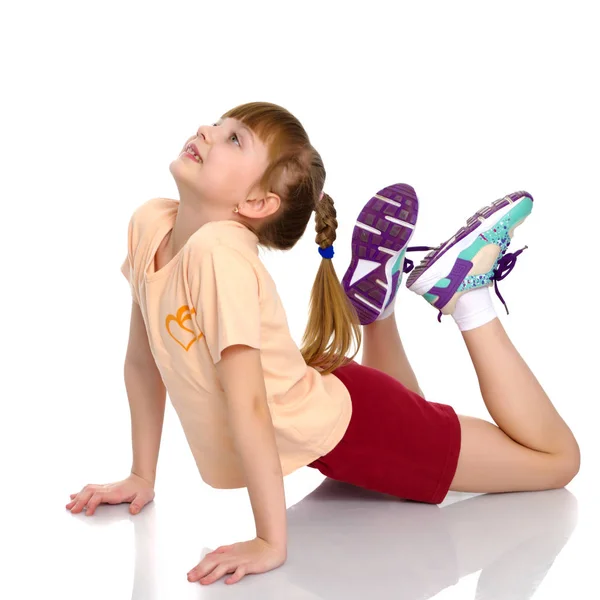 Een klein meisje doet gymnastiek oefeningen. — Stockfoto