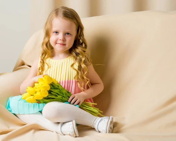 Mooi schoolmeisje met lang zijdezacht haar met een boeket tulpen — Stockfoto