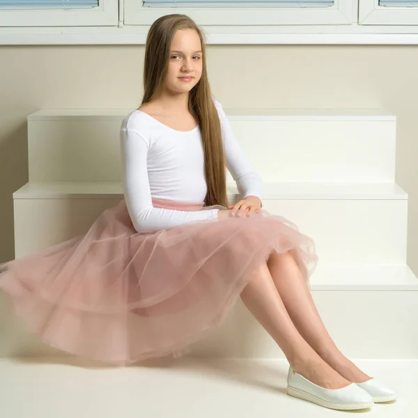 Schöne kleine Mädchen sitzt auf der weißen Treppe. — Stockfoto
