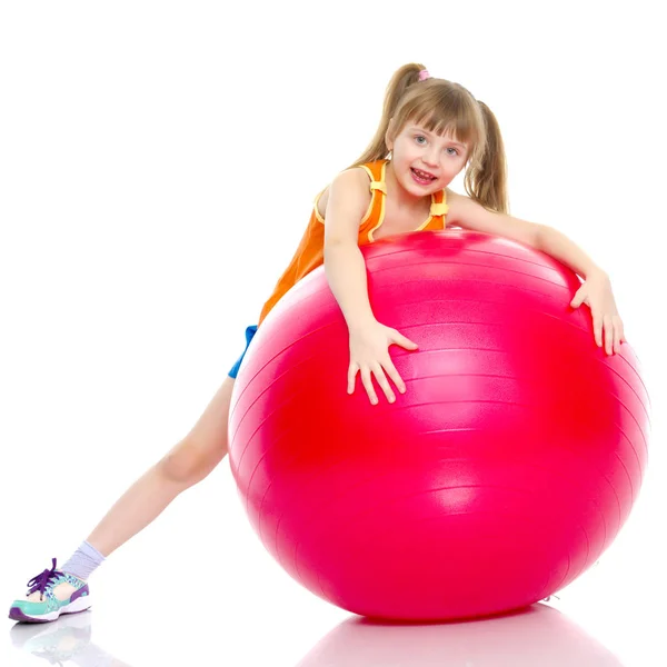 Kleines Mädchen macht Übungen auf einem großen Ball für Fitness. — Stockfoto