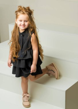 Küçük bir kız beyaz bir merdivende duruyor..