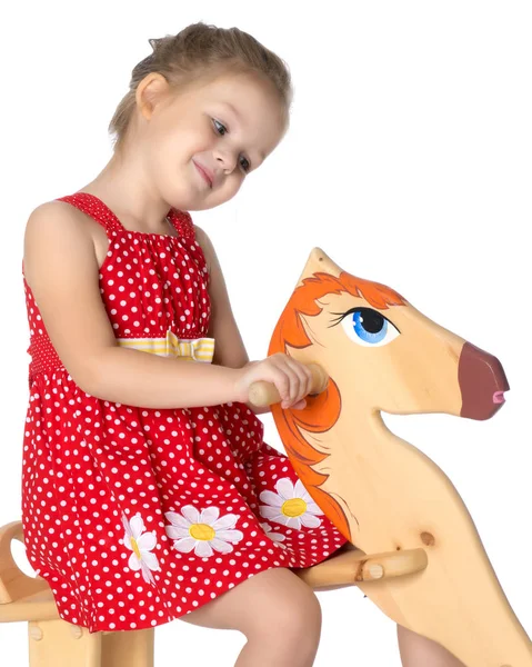 Girl swinging on a wooden horse. — Stock Photo, Image