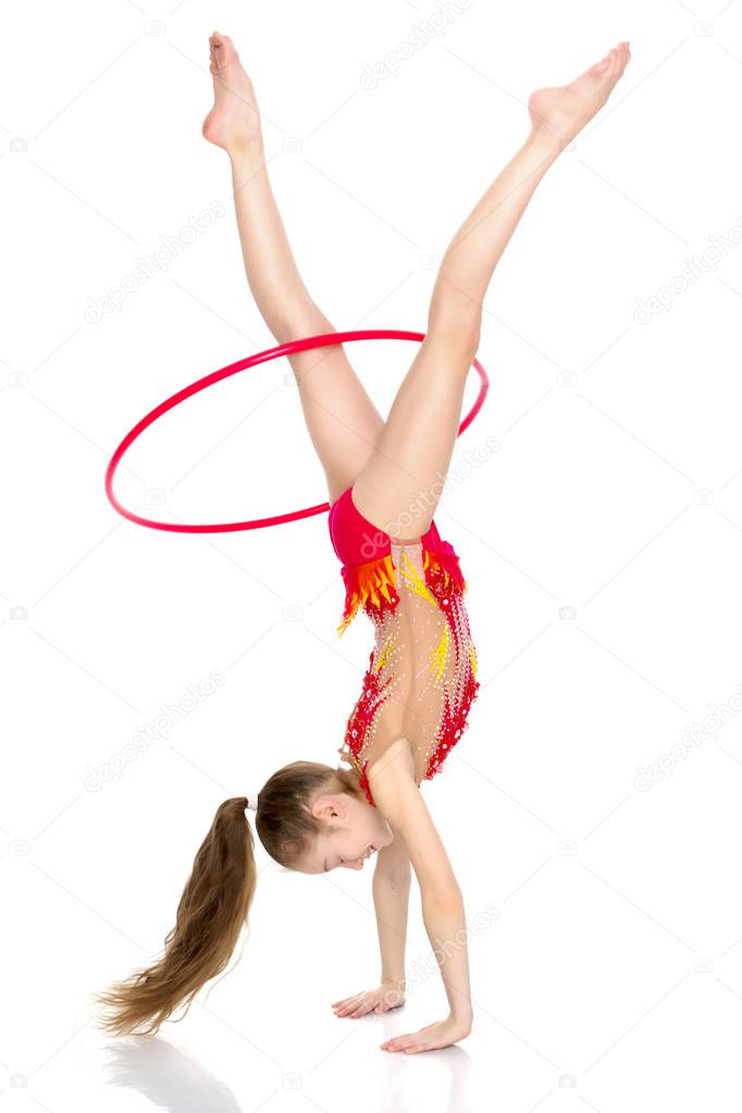 A girl gymnast performs an exercise with a hoop.