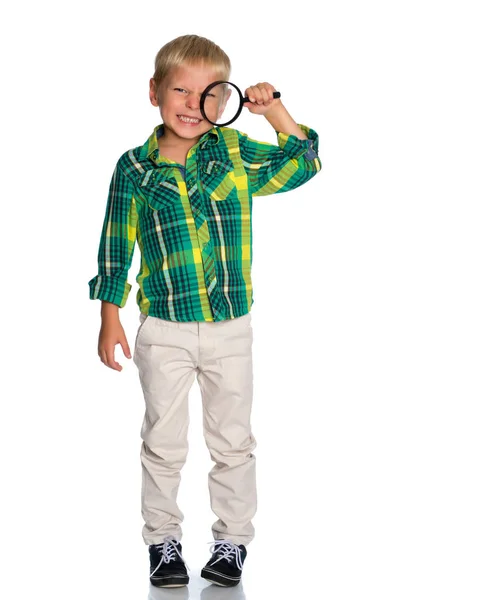 En liten pojke ser genom ett förstoringsglas. — Stockfoto