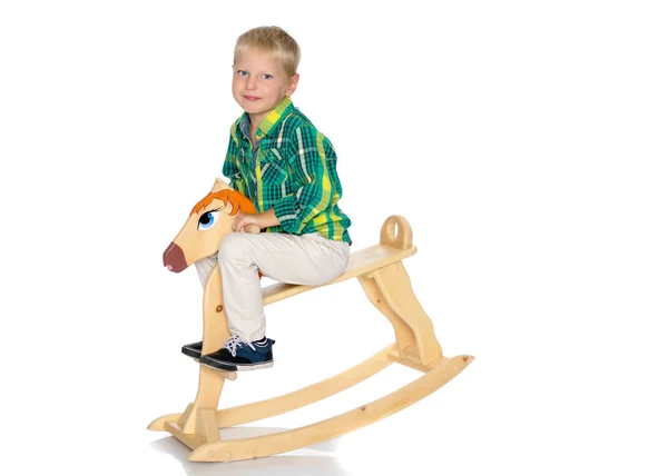 Un ragazzino sta cavalcando un cavallo di legno — Foto Stock