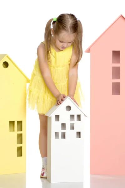 Little girl is playing with wooden houses. — Stock Photo, Image