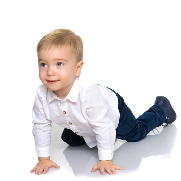 Een kleine jongen is liggend op de vloer in de studio. — Stockfoto