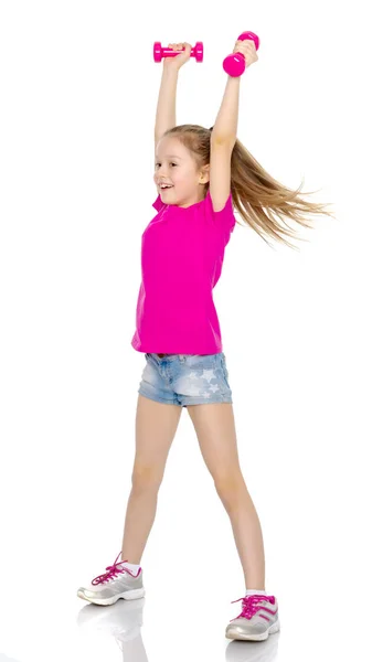 Маленькая девочка делает упражнения с гантелями. — стоковое фото