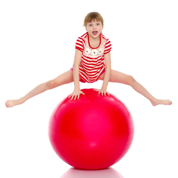 En liten flicka hoppar på stora gym ball. — Stockfoto