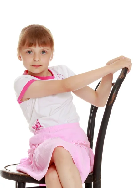 Menina está sentada em uma cadeira — Fotografia de Stock