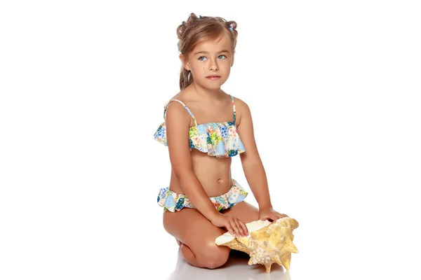 Little girl in a swimsuit with a seashell — Stock Photo, Image