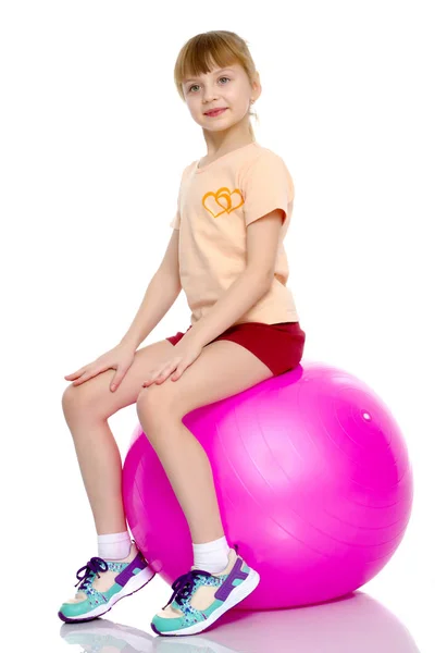 小さな女の子が大きなジム ボールにジャンプして. — ストック写真
