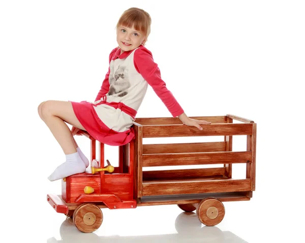 Kleines Mädchen spielt mit einem Holzauto. — Stockfoto