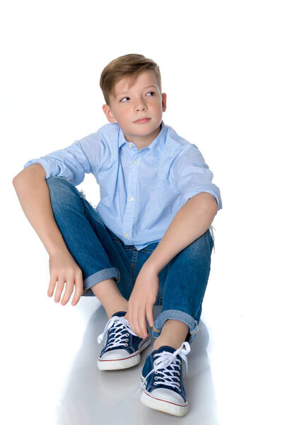 Модный мальчик-подросток сидит на полу
.