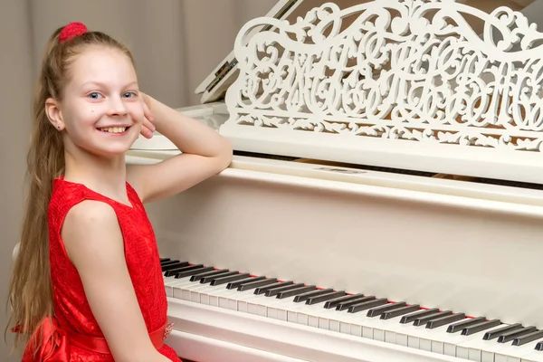 The girl is at the white grand piano. — Stock Photo, Image
