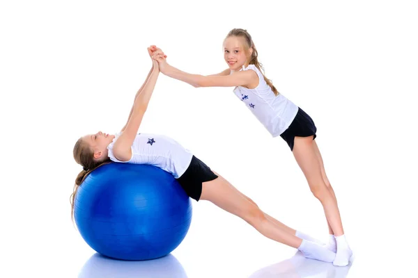 Chicas gimnastas realizan ejercicios con una pelota grande para la aptitud . — Foto de Stock