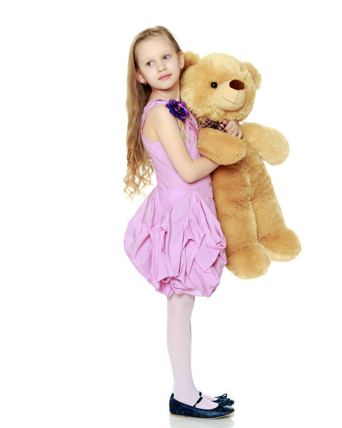 Beautiful little girl 5-6 years.She is holding a large teddy bea