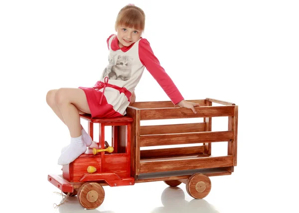 Liten flicka leker med en bil i trä. — Stockfoto