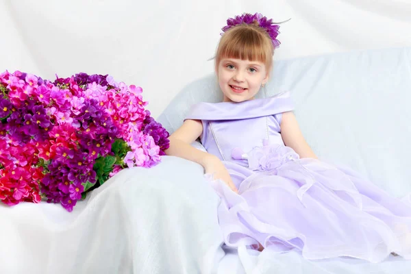 Girl sits next to a bouquet of flowers. — Stock Photo, Image