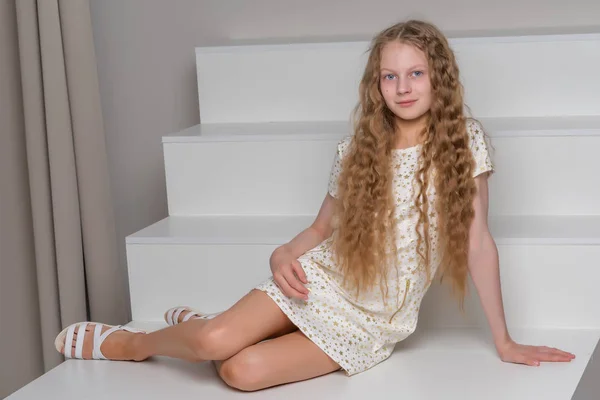 Hermosa niña está sentada en la escalera blanca. —  Fotos de Stock