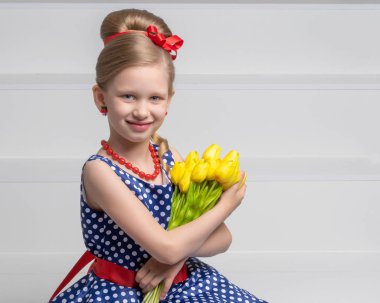 Lale bir buket ile küçük bir kız merdivende oturuyor.