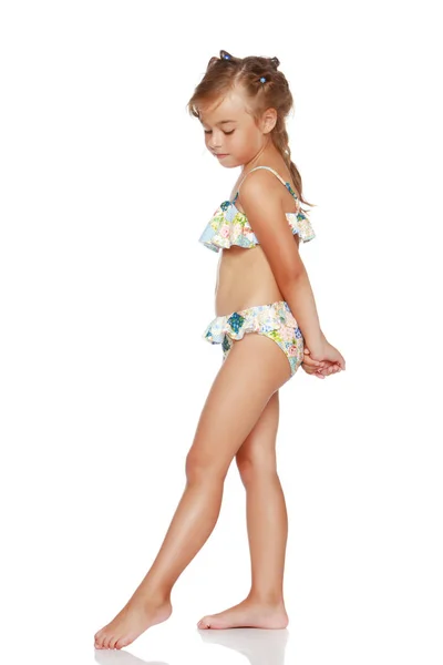 Little girl in a swimsuit is sitting on a pillow ⬇ Stock Photo Image