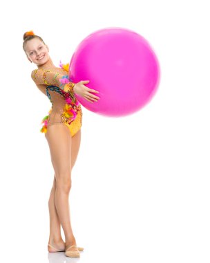 Küçük kız spor yapmak için büyük bir top üzerinde egzersiz yapıyor..