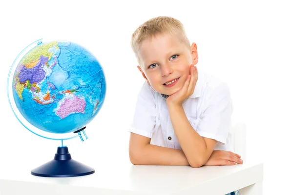 Um menino está estudando geografia em um globo . — Fotografia de Stock