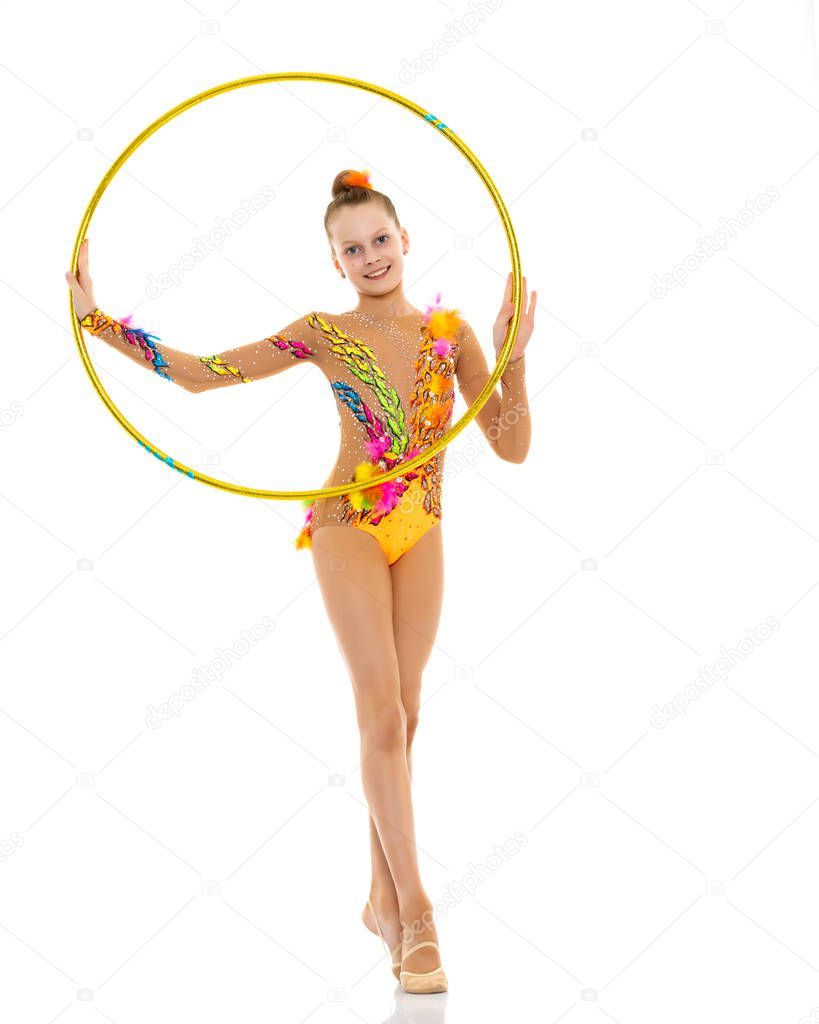 A girl gymnast performs an exercise with a hoop.