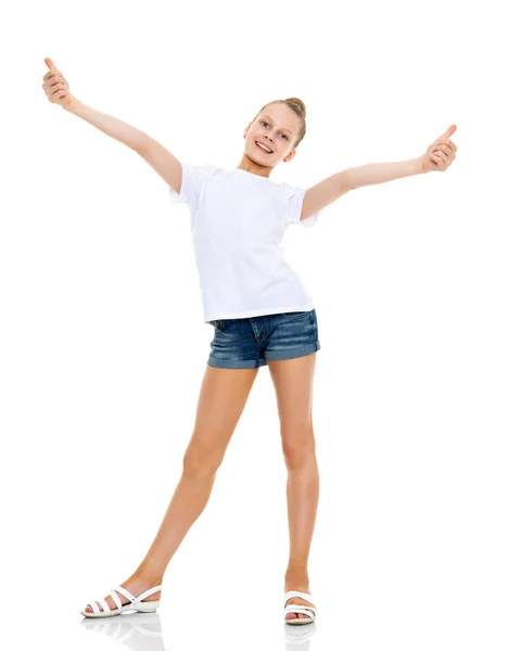 Una niña con una camiseta blanca sostiene su pulgar hacia arriba . —  Fotos de Stock