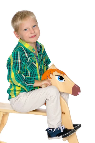 Un niño está montando un caballo de madera —  Fotos de Stock