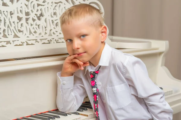 Liten pojke i studio nära vit piano. — Stockfoto