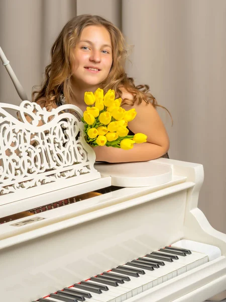 Girl with flowers near a white piano.