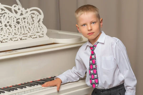 Liten pojke i studio nära vit piano. — Stockfoto