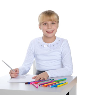 Küçük bir kız masada çizim.