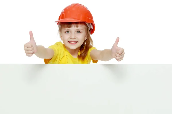 Дівчина в будівельному шоломі дивиться з-за рекламного щита . — стокове фото