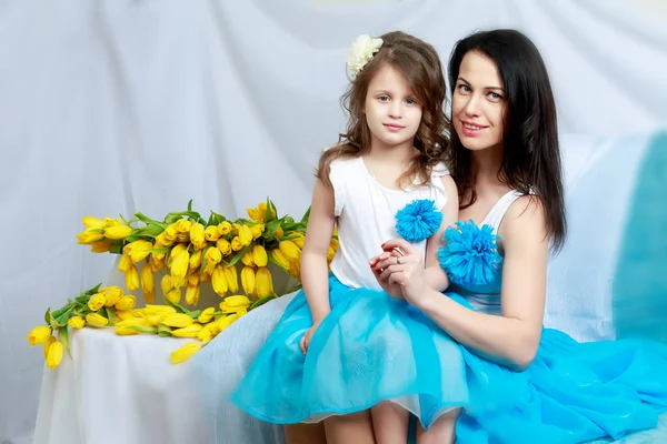 妈妈和女儿在沙发上用一束鲜花. — 图库照片