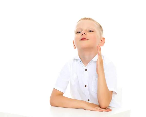 Un petit garçon à la table de l'école fait ses devoirs . — Photo