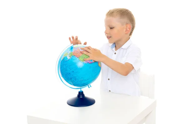 Um menino está estudando geografia em um globo . — Fotografia de Stock