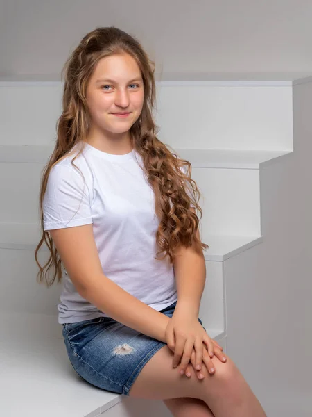 Dospívající dívka sedí na bílé schodiště. — Stock fotografie