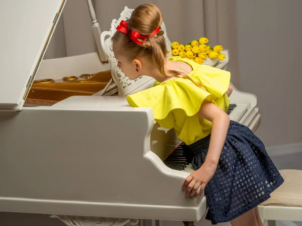 Girl schoolgirl near the piano on which lies a bouquet of flower — Stock Photo, Image