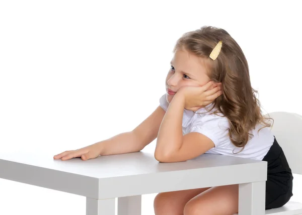 A menina está sentada à mesa — Fotografia de Stock