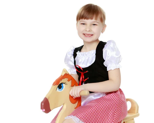 Menina balançando em um cavalo de madeira . — Fotografia de Stock