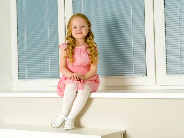 Küçük bir kız pencerenin arka plan üzerine oturuyor — Stok fotoğraf