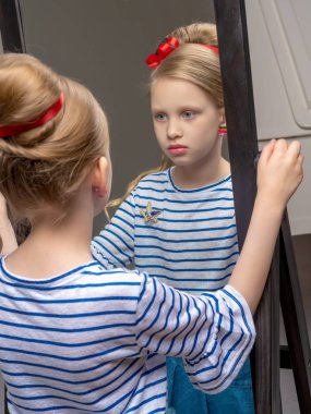 Ayna yakınındaki küçük bir kız ruj dudakları boyalar