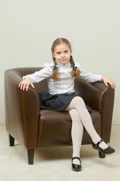 Uma menina está sentada em uma cadeira . — Fotografia de Stock