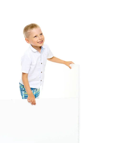 Een kleine jongen is op zoek achter een lege banner. — Stockfoto